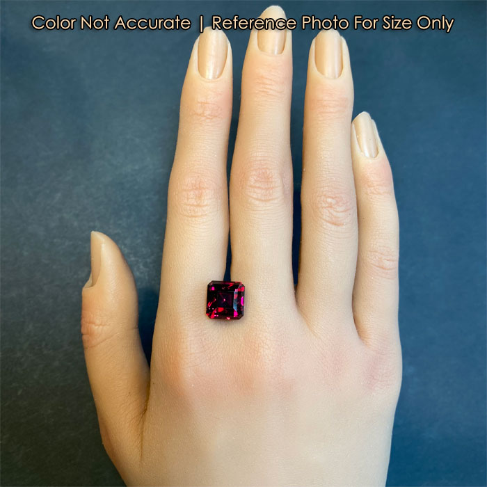 violet red square step cut garnet gem on hand