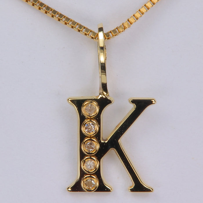 yellow gold K pendant with bezel set diamonds