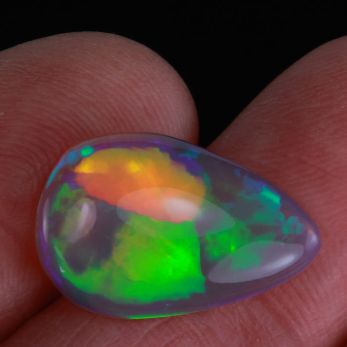 colorful opal gemstone pear shape in hand
