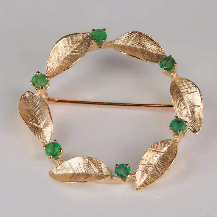 yellow gold estate pin with leaf details in wreath shape with emerald gemstones