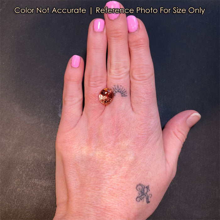 oval cut peach tourmaline gem on hand