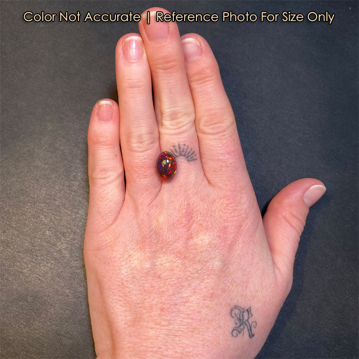 oval black opal gemstone on hand