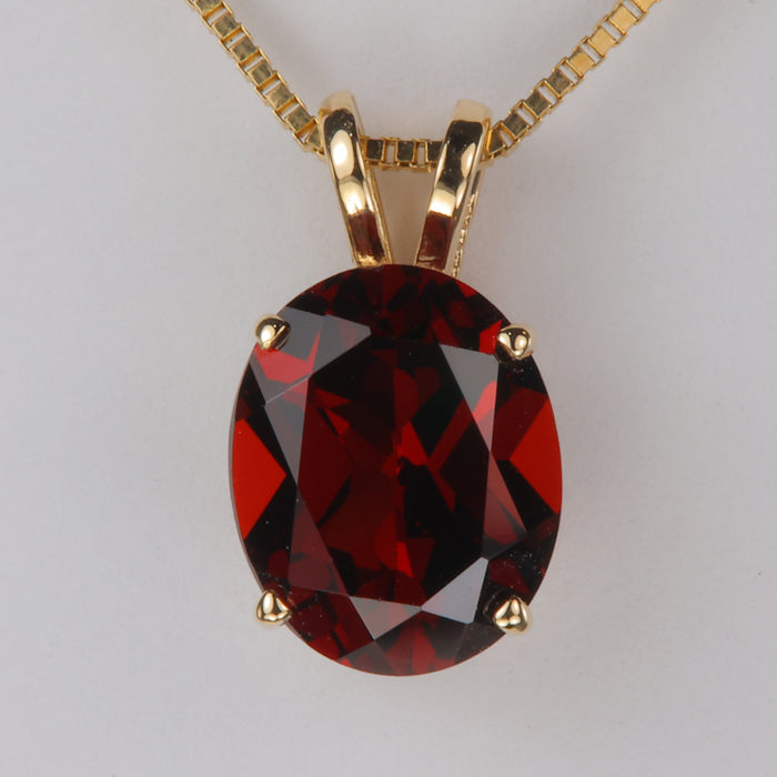 deep red color oval cut garnet gemstone pendant in yellow gold 