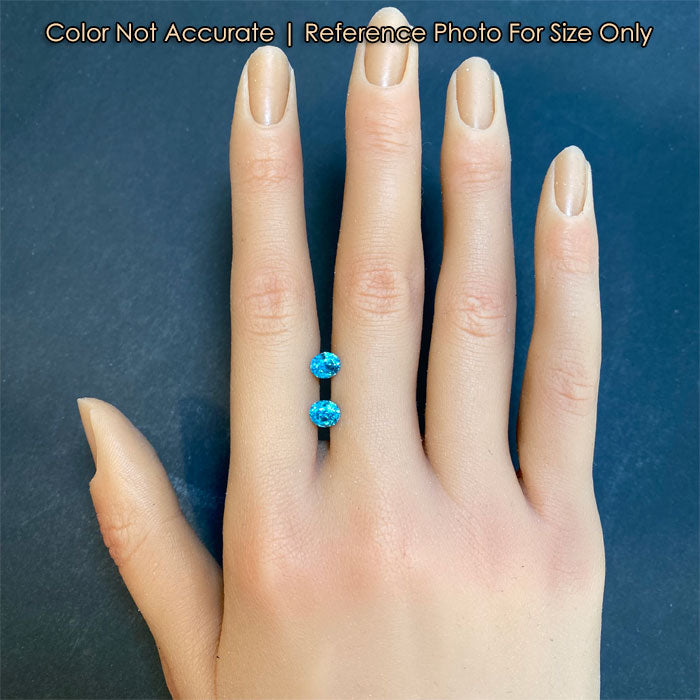 blue zircon gemstone pair on hand